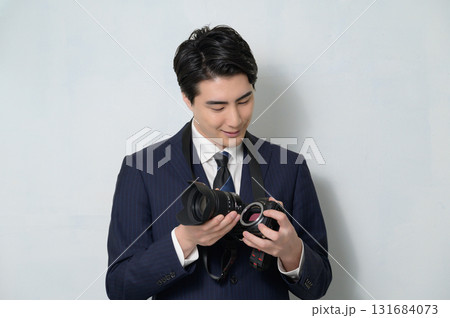 カメラのレンズを交換するスーツの男性 131684073