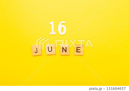 Top view of word 16 June calendar date made by wooden cubes on yellow color background 131684657