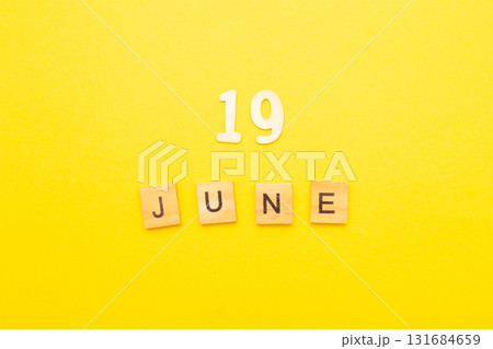 Top view of word 19 June calendar date made by wooden cubes on yellow color background 131684659