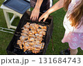 Kida grilling chicken on a barbecue grill in a backyard during summer holidays. 131684743