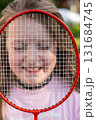 Girl holding badminton racket in front of face smiling with eyes closed 131684745