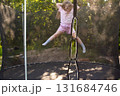 Child girl jumping on trampoline outdoors in the yard on summer vacation. 131684746