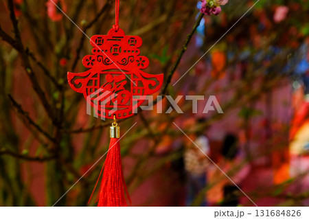Close-up of the Chinese decoration hanging on the peach blossom plant. Chinese New year celebration. Festive decoration and celebration. For background use. 131684826