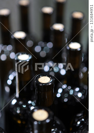 Bottles of wine without labels. Young wine in bottles without labels. Craft winery. A large number of bottles of wine. Selective focus. Bottles of wine without labels. Young wine in bottles without labels. Craft winery. A large number of bottles of wine. Selective focus. 131684951