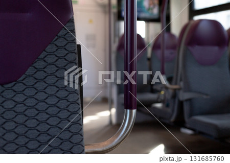 Modern train interior featuring purple colored seats and grab poles. Sleek design reflects contemporary public transport aesthetics, offering comfort and style for passengers during travels Modern train interior featuring purple colored seats and grab poles. Sleek design reflects contemporary public transport aesthetics, offering comfort and style for passengers during travels 131685760