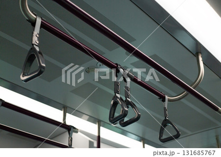 Train handrails and straps in modern transportation system. The image emphasizes metal and fabric design of the hand grips, showcasing practical and functional element of public transit Train handrails and straps in modern transportation system. The image emphasizes metal and fabric design of the hand grips, showcasing practical and functional element of public transit 131685767