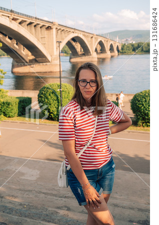Woman in Striped Shirt Posing by River Bridge 131686424