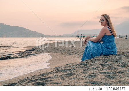 Woman sits on the beach and looks at the sea in Alanya city 131686471