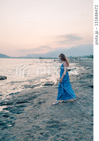 Woman sits on the beach and looks at the sea in Alanya city 131686472