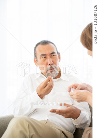 不安そうな表情で薬を飲むシニア男性 131687126