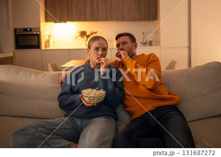 Fearful shocked couple watch thriller movie with popcorn at home. Family scared movie night 131687272