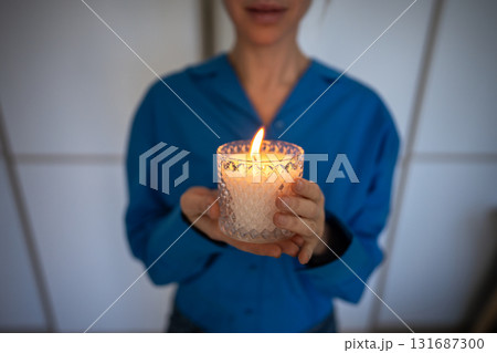 Woman holding scented candle with essential oils for stress relief meditation. Self care routine. Woman holding scented candle with essential oils for stress relief meditation. Self care routine. 131687300