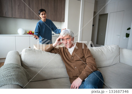 Tired husband sit indifferent on sofa ignoring raging angry meticulous wife shouting blaming Tired husband sit indifferent on sofa ignoring raging angry meticulous wife shouting blaming 131687346