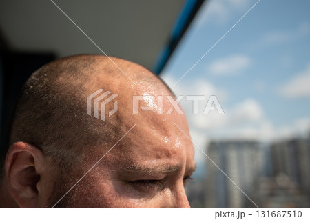 Sweat broke out on forehead of overweight man in hot weather standing in sun. 131687510
