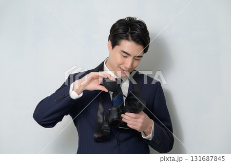 カメラのメンテナンスをするスーツの男性 131687845