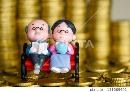 Elderly couple figurines on bench with coins symbolizing retirement savings and pension planning 131689401
