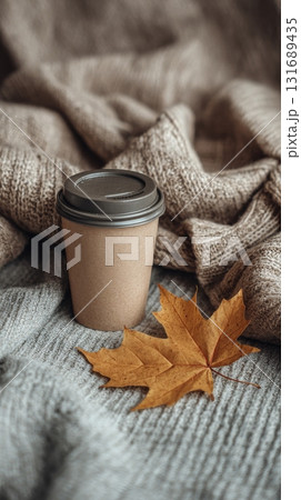 Cozy autumn setting with eco coffee cup take away and fall leaf on warm fabric, generated AI 131689435