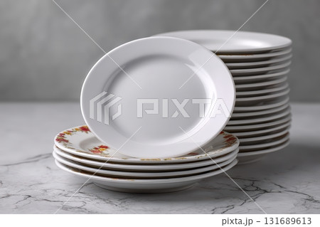 Stacked white plates with floral design on a marble surface in a kitchen setting Stacked white plates with floral design on a marble surface in a kitchen setting 131689613