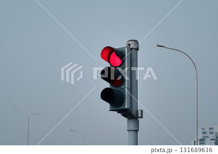 Traffic signal displaying red light at an urban intersection on a cloudy day 131689616