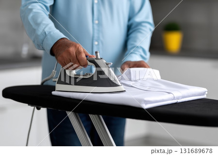 Ironing a white shirt at home in a modern kitchen on a sunny day 131689678