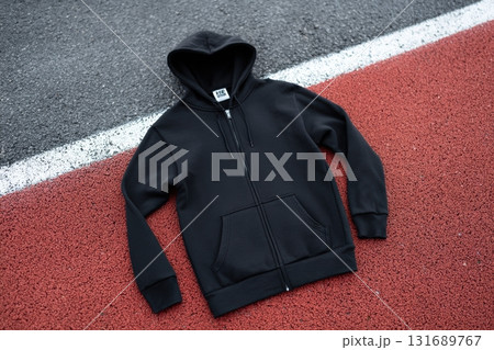 Black hoodie laid out on a red running track during daytime Black hoodie laid out on a red running track during daytime 131689767
