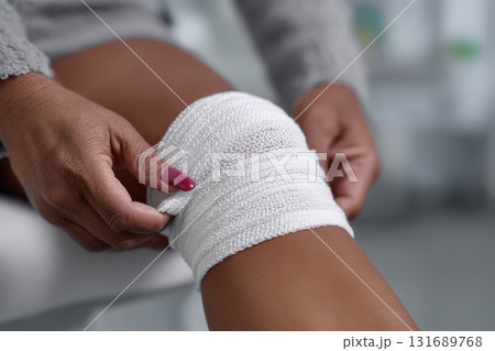 Patient receives bandaging on a knee at a medical facility during a routine check-up 131689768
