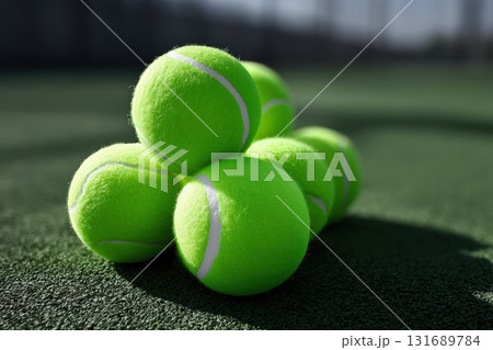 Bright green tennis balls stacked on a court in sunlight during a warm afternoon 131689784