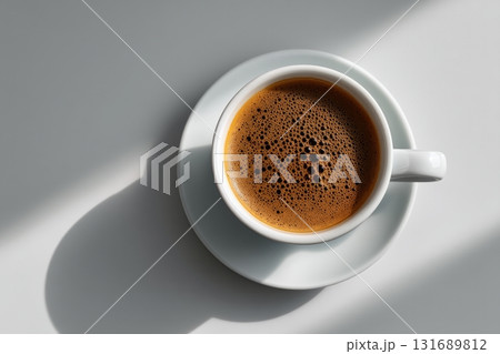 Detailed view of a freshly brewed coffee cup on a white saucer in bright sunlight 131689812