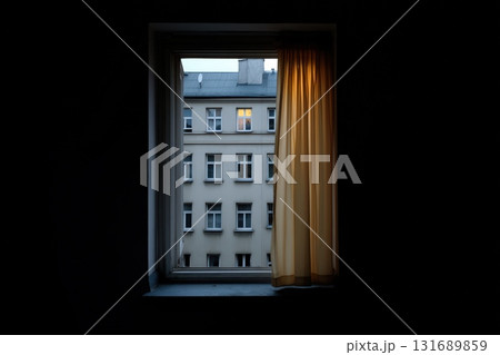 Late evening view through a window with a lit apartment in the distance 131689859