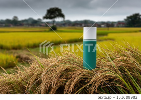Bottle of vibrant liquid stands among lush rice fields at twilight 131689982