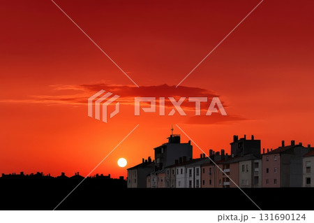 Sunset over buildings creates a warm glow in the evening sky 131690124