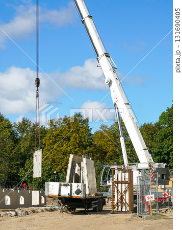 Crane lifting precast wall panel at residential building construction site with workers 131690405