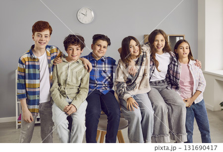 Group portrait of happy classmates and friends sitting on a table in the classroom Group portrait of happy classmates and friends sitting on a table in the classroom 131690417
