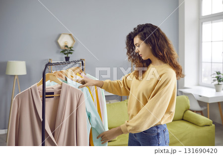 Pretty young woman choosing clothes at wardrobe at home Pretty young woman choosing clothes at wardrobe at home 131690420