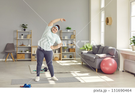 Overweight chubby woman doing side bends at home Overweight chubby woman doing side bends at home 131690464