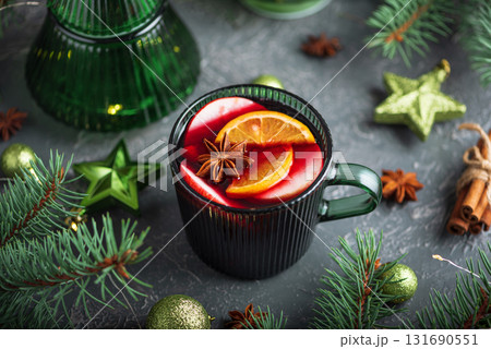 Holiday Mulled Wine with Orange and Apple in Green Mug Surrounded by Christmas Decor 131690551