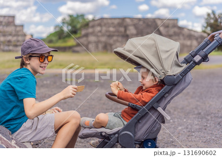 Two brothers as tourists in front of the Teotihuacan pyramids in Mexico, enjoying family travel, cultural heritage, and sightseeing together Two brothers as tourists in front of the Teotihuacan pyramids in Mexico, enjoying family travel, cultural heritage, and sightseeing together 131690602