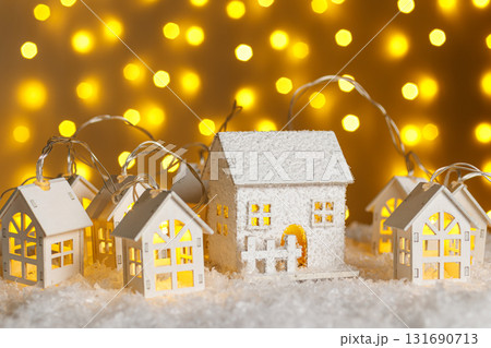 Christmas wooden houses garlands with lights in the snow on glowing lights bokeh background 131690713