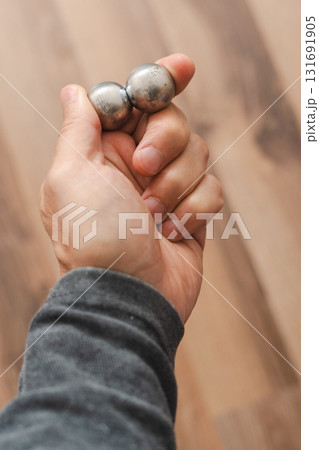A man's hand holds two CNC metal spheres in warm daylight. A symbol of Earth's poles and the power to control their balance. Precision meets metaphor. A man's hand holds two CNC metal spheres in warm daylight. A symbol of Earth's poles and the power to control their balance. Precision meets metaphor. 131691905