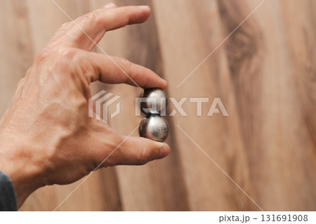 A man's hand holds two CNC metal spheres in warm daylight. A symbol of Earth's poles and the power to control their balance. Precision meets metaphor. 131691908