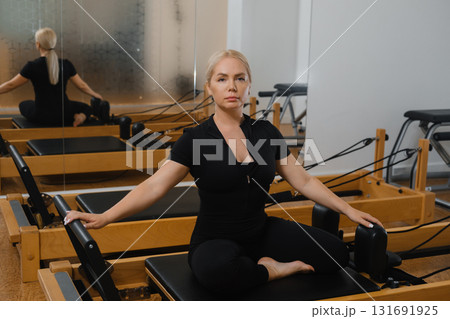 Pilates session in a modern studio focusing on flexibility and core strength with an instructor demonstrating proper technique Pilates session in a modern studio focusing on flexibility and core strength with an instructor demonstrating proper technique 131691925
