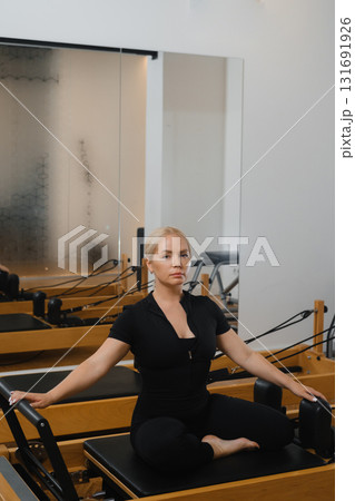 Pilates class in a modern studio with a focused instructor demonstrating an exercise during a morning session Pilates class in a modern studio with a focused instructor demonstrating an exercise during a morning session 131691926