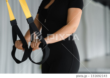 Fitness enthusiast engages in suspension training in a modern gym setting during an afternoon workout session 131692143