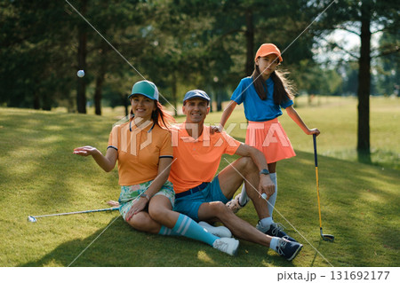Family enjoys a fun day of golf wearing colorful outfits on a sunny afternoon at a lush golf course near the city 131692177