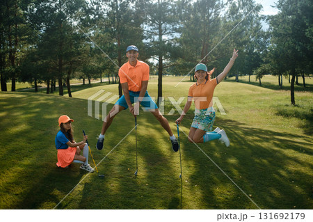 Group of friends enjoying a playful moment on a golf course during a sunny afternoon featuring colorful golf attire and a lush green landscape Group of friends enjoying a playful moment on a golf course during a sunny afternoon featuring colorful golf attire and a lush green landscape 131692179