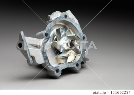 Top-quality parts for your car. Car maintenance. New water pump for a car's engine cooling system on a gray gradient background. 131692254
