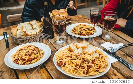 Rustic wooden table laden with pasta dishes, bread, and red wine Rustic wooden table laden with pasta dishes, bread, and red wine 131692636