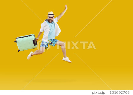 Happy man hurrying on summer holiday, holding suitcase and jumping up on yellow background Happy man hurrying on summer holiday, holding suitcase and jumping up on yellow background 131692703
