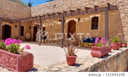 Sunny courtyard of a traditional Mediterranean stone house with flowering pots 131693249