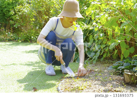 エプロン姿で庭の手入れをする女性 131693375
